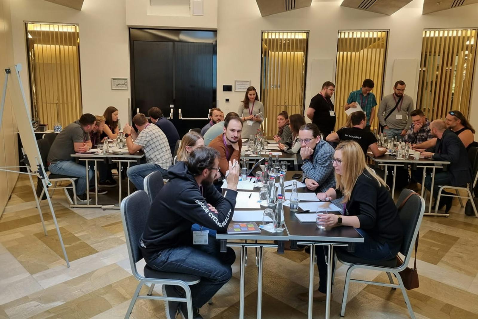 Groups on people collaborating around four tables at a workshop event